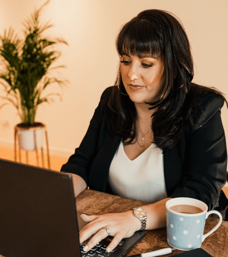 Woman using laptop whilst drinking a cup of tea